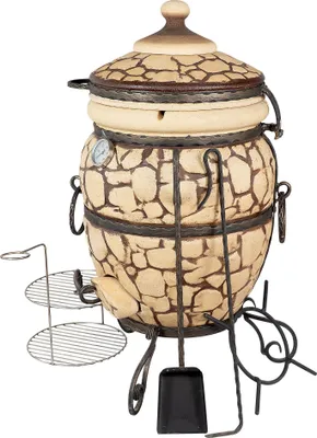 A traditional tandoor oven on a stand, with accessories.