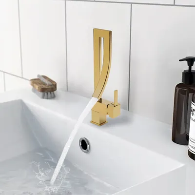 A modern gold faucet with water flowing into a white sink.