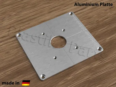 A silver aluminum plate with markings and a central hole, placed on a wooden surface.
