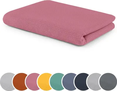 A folded pink waffle-knit blanket is shown on a white background. Below the blanket are circular swatches of various colors, presumably representing other available colors for the product.