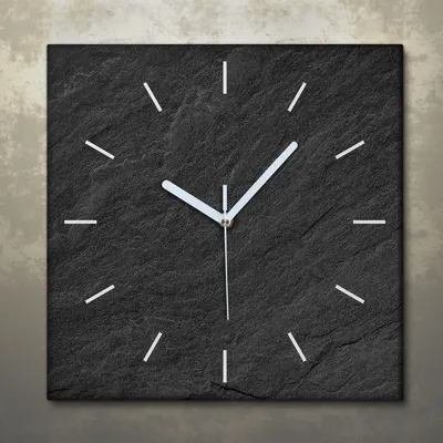 A square clock with a black slate-like face and white hour markers and hands.