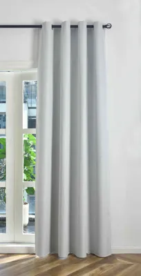 A light gray blackout curtain hangs in front of a window, covering most of the frame. The curtain is pleated and extends from a black curtain rod to the floor. The floorboards are visible at the bottom of the image.