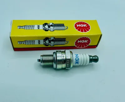 A spark plug and its packaging are displayed on a light gray surface.