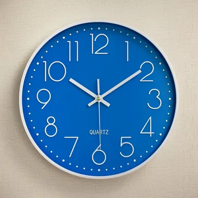 A blue wall clock with white numbers and hands is mounted on a textured light gray wall.