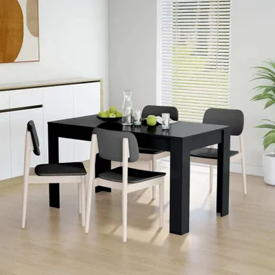 A dining room scene with a black table and four chairs, set with a carafe of water and some apples.