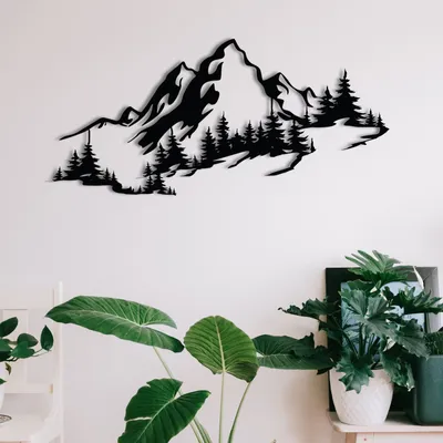A black metal mountain silhouette wall art is displayed on a white wall above several large green houseplants.