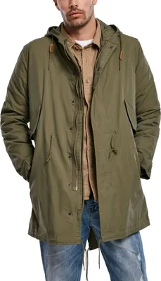A man wearing a green parka and blue jeans.