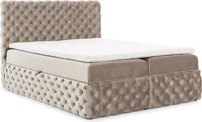 A tufted beige boxspring bed with a white mattress topper, shown from a side-angle on a white background.