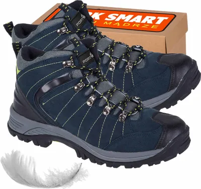 A pair of navy blue hiking boots are displayed in front of a cardboard box with the brand name visible.