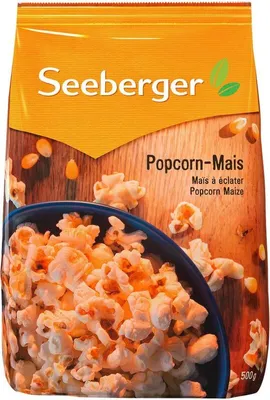 A bag of popcorn with a bowl of popcorn in the foreground.