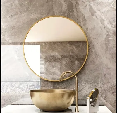 A modern bathroom vanity with a round gold-framed mirror above a gold basin sink and a brass faucet.