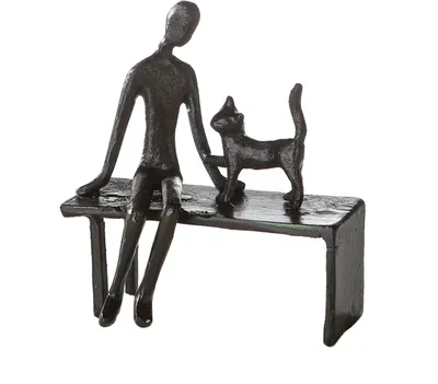 A dark, stylized sculpture of a person sitting on a bench with a cat standing next to them.