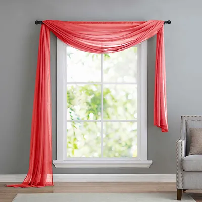 A sheer red scarf draped over a window.