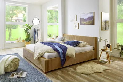 A bedroom with a bed, windows overlooking a garden, and decorative items.