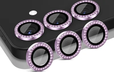 A set of camera lens protectors with decorative rhinestones on a dark smartphone.