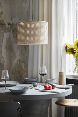 A dining table set for a meal, with a pendant lamp overhead and sunflowers in the background.