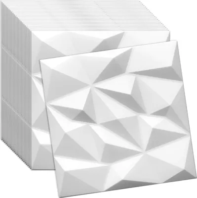 A stack of white 3D wall panels with a geometric design, with one panel placed in front.