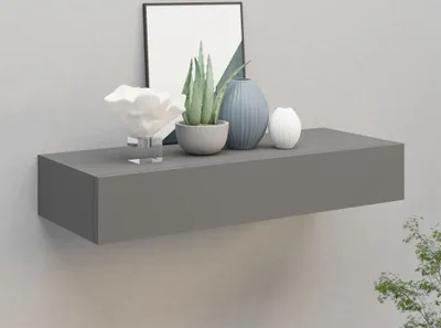 A grey floating shelf mounted on a light grey wall, decorated with various vases and a potted plant. A framed picture is visible behind the shelf.