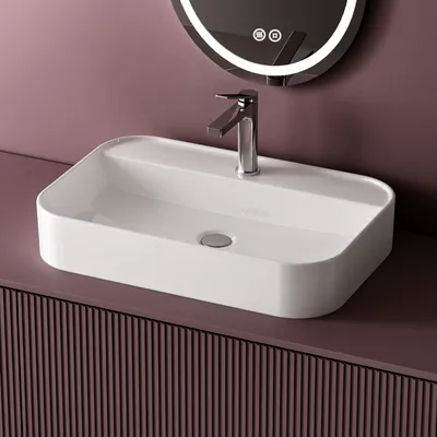 A white ceramic sink with a chrome faucet is shown on a purple vanity with a ribbed texture. A circular mirror with LED lighting is visible in the background.