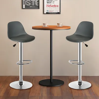 Two gray bar stools are placed around a small round table with two cups on it. There are framed posters on the wall behind the table.