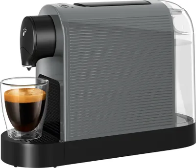 A grey Tchibo Cafissimo coffee machine with a glass cup of espresso in front of it.