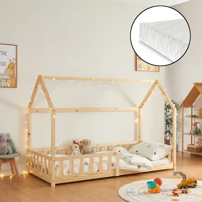 A children's house bed with a mattress and fairy lights in a room.