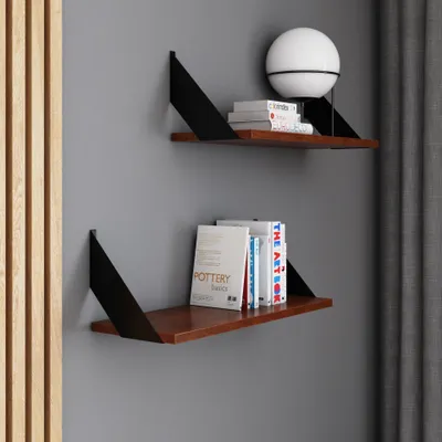 Two modern shelves mounted on a gray wall, displaying books and a lamp.