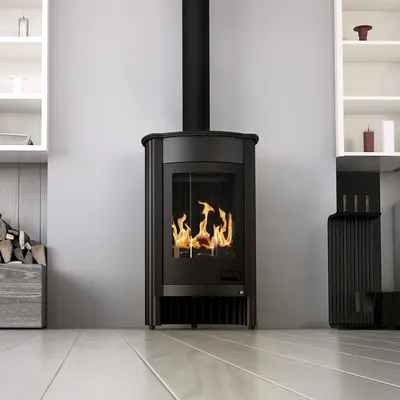 A black freestanding fireplace with flames visible inside, set against a light gray wall with white shelving units on either side. The floor is made of light-colored wooden planks.