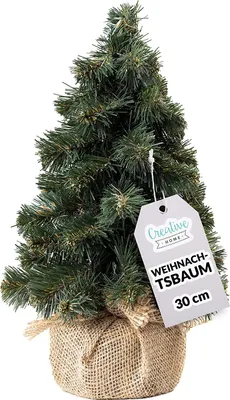A small artificial Christmas tree in a burlap pot with a tag.
