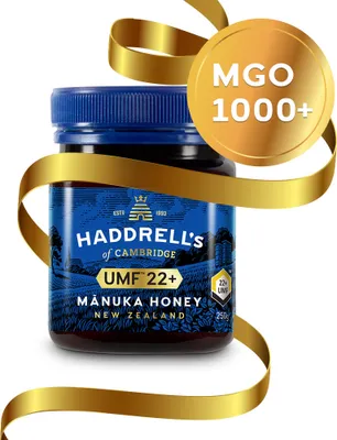 A jar of manuka honey is presented with a golden ribbon and a circular badge.