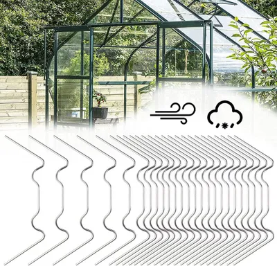 A greenhouse with a wooden fence in the background, and a row of metal clips in the foreground.
