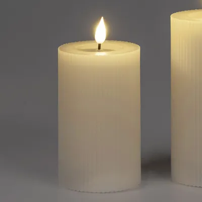 A close-up of a cream-colored LED candle with a flame.