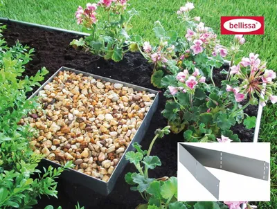 A garden bed with a metal edging, filled with gravel and surrounded by plants and flowers.