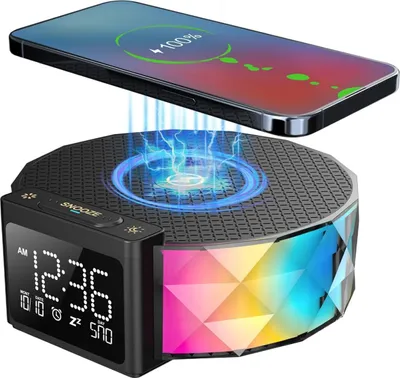 A digital alarm clock with a wireless charging pad and a smartphone being charged.