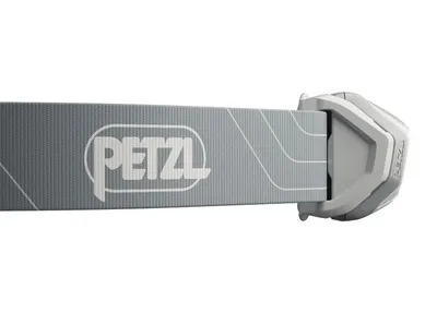 A close-up side view of a grey PETZL branded headlamp strap with a white logo and a white geometric pattern, attached to a grey plastic buckle mechanism.