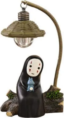 A figurine of a character from Japanese animation, holding a small blue creature, with a lamp above it, set against a white background.