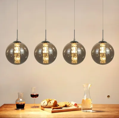 A set of four pendant lights hanging above a table with food and drink.