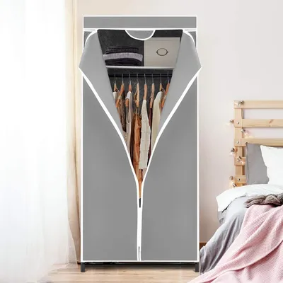 A gray fabric wardrobe with clothes hanging inside, placed next to a bed.