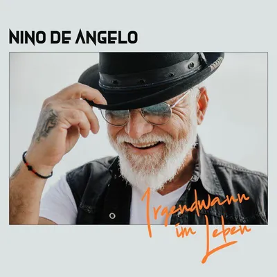 A man wearing a hat and sunglasses, smiling.