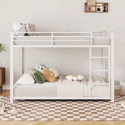 A white metal bunk bed with mattresses and pillows, set up in a room with a checkered rug.