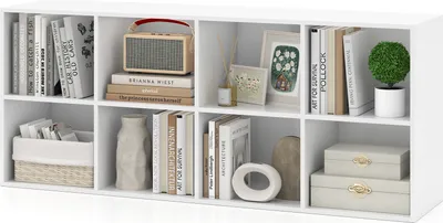 A white cube storage unit filled with books, decorative items, and storage baskets.