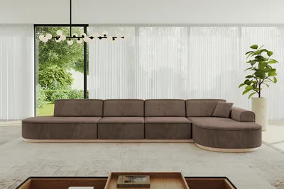 A modern living room with a large sectional sofa in front of a window with sheer curtains.