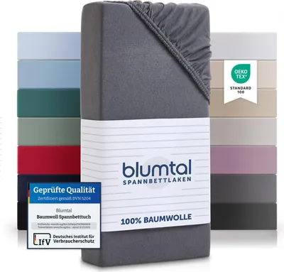 A stack of folded fitted sheets in various colors, with a close-up of a gray fitted sheet in the foreground.