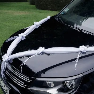 Detailansicht der weißen Hochzeitsgirlande mit Rosenblüten entlang der Motorhaube eines Fahrzeugs.