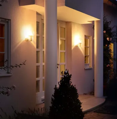 A house exterior at dusk, with wall-mounted lights illuminating the entrance.