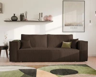 A modern living room scene featuring a brown corduroy sofa with throw pillows, a side table, a shelf with decorative items, and a framed poster on the wall.