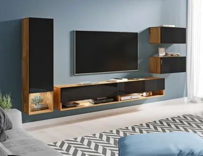 A modern living room setup featuring a wall-mounted entertainment unit with a television, shelves, and cabinets, illuminated by LED lighting.