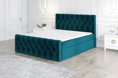 A teal upholstered boxspring bed with a white mattress is shown in a well-lit room with white walls and doors.