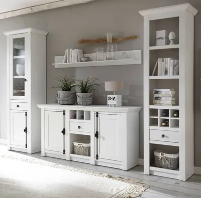 A white living room furniture set, including a display cabinet, sideboard, and tall bookshelf, arranged against a gray wall.