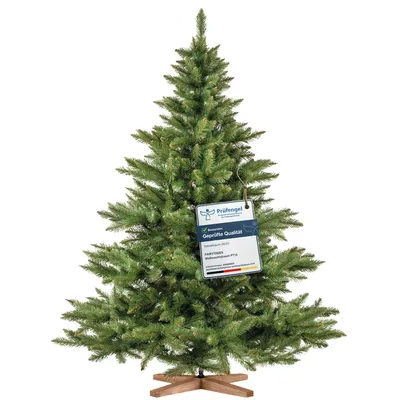 A green artificial Christmas tree with a wooden stand and a quality certification tag.
